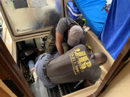 Two men trying to loosen a fuel filter.